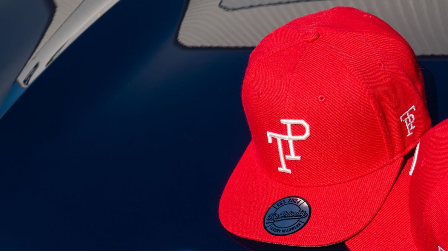 Dark green TP baseball cap with white embroidered logo resting on matte green Mercedes-Benz G-Wagon hood.